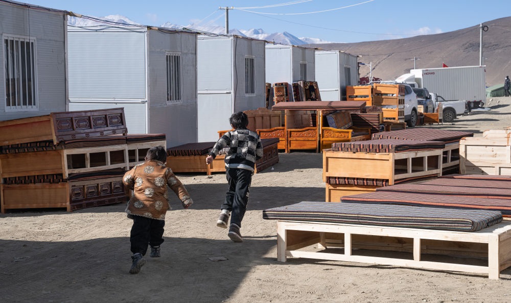 2025年1月13日，在定日縣嘎旦村，兩個(gè)孩子在剛運(yùn)來的兩排藏床間奔跑。新華社記者丁增尼達(dá) 攝