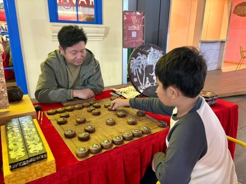 柯秋楓與市民下椰雕象棋。人民網 陳葉欣攝