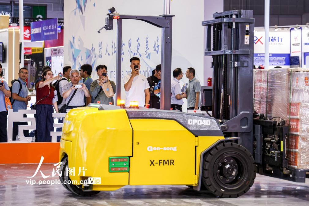 第24屆中國工博會現(xiàn)場，觀眾觀看叉取機器人作業(yè)演示。王初攝（人民圖片網(wǎng)）