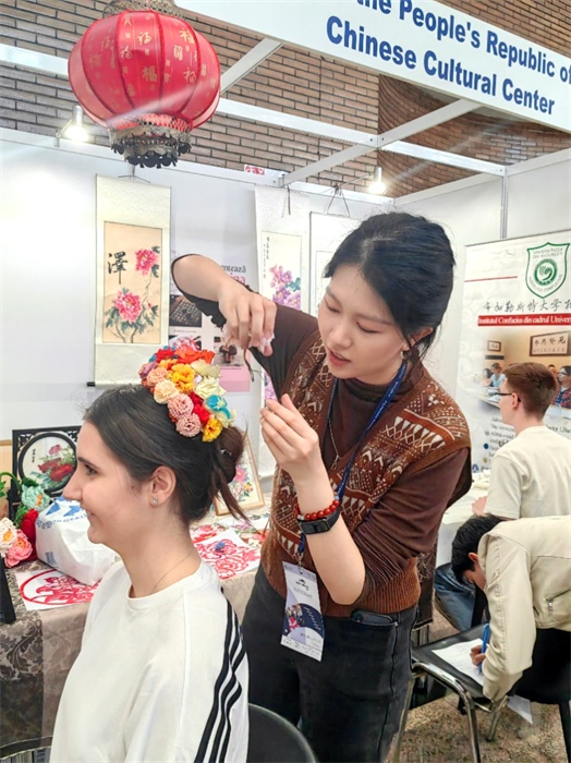 展覽正值羅馬尼亞迎春花節(jié)，國際中文教師志愿者潘婧穎向游客們介紹了國家非物質(zhì)文化遺產(chǎn)——福建泉州的簪花文化。布加勒斯特大學(xué)孔子學(xué)院供圖。