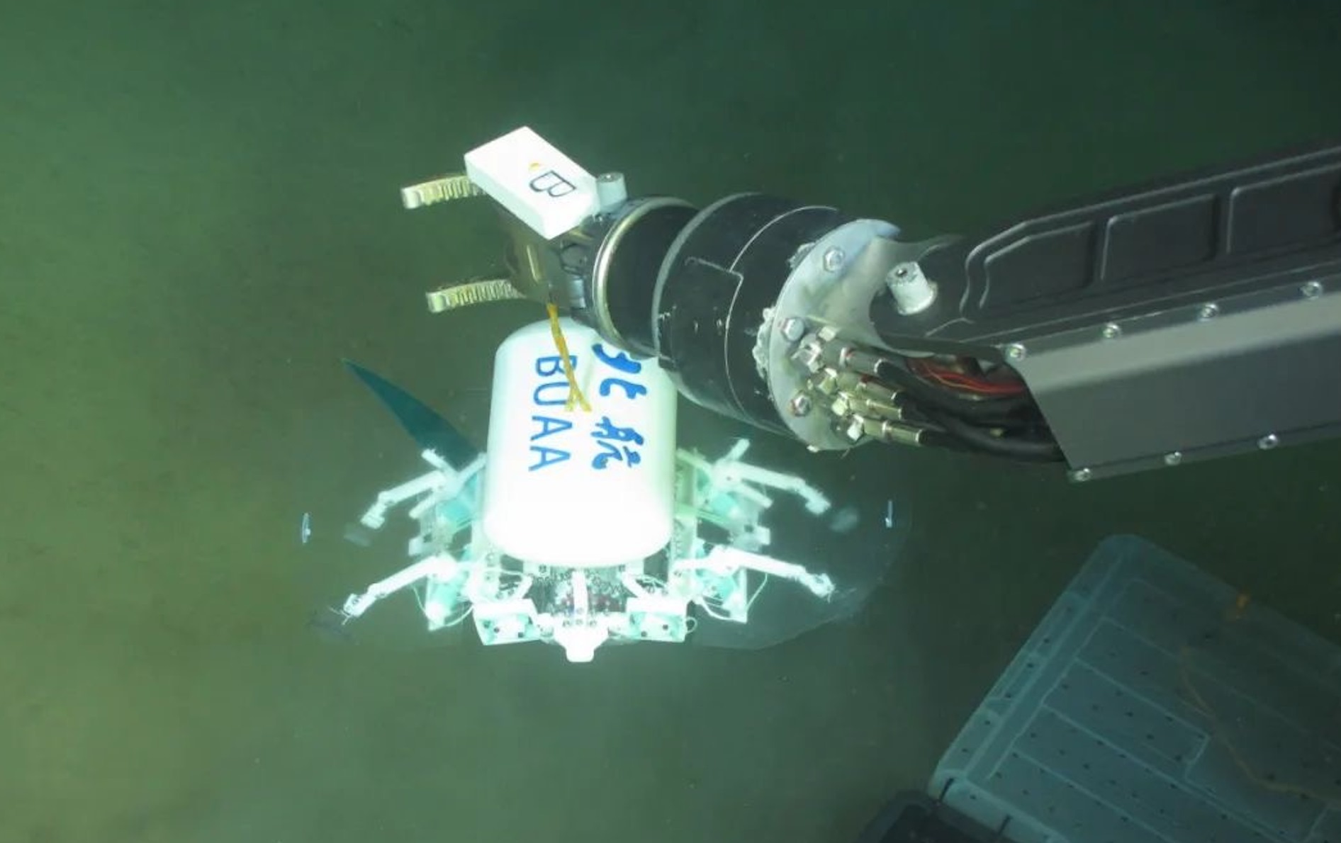 科研人員利用機(jī)械臂將北航深海小型機(jī)器人投于馬里亞納海溝。校方供圖