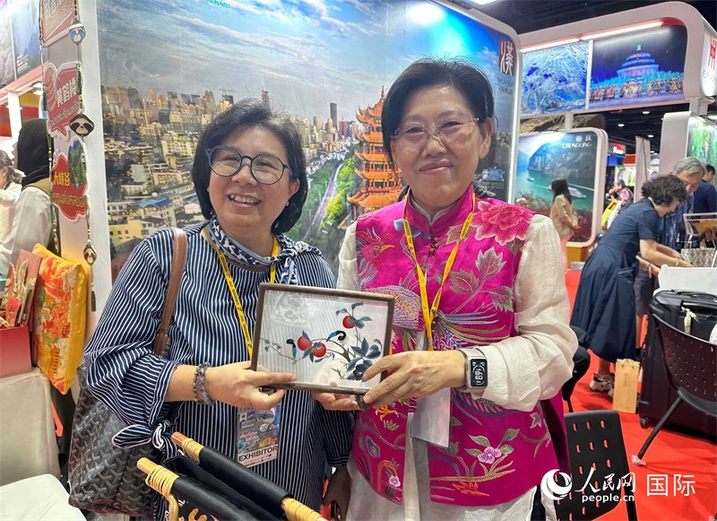 中國(guó)“大冶刺繡”傳承人劉小紅（右）參加泰國(guó)國(guó)際旅游展，向觀眾介紹中國(guó)非遺刺繡針?lè)?。人民網(wǎng)記者 簡(jiǎn)承淵攝
