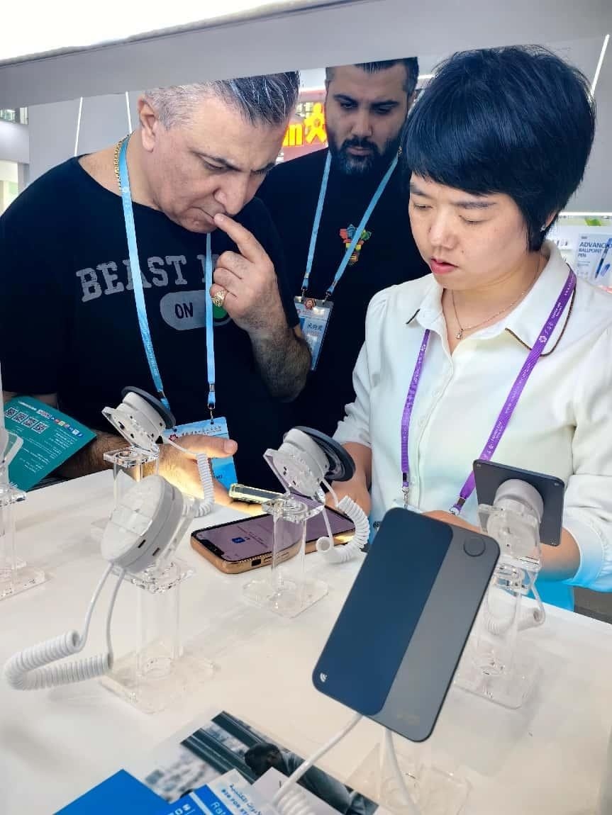 展臺工作人員向外商展示“AI TOP翻譯終端”。圖片來源：受訪者提供