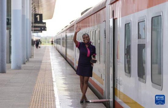 5月31日，在蒙內(nèi)鐵路內(nèi)羅畢站，一名乘務(wù)員在即將開往蒙巴薩的E2次列車旁等候乘客。新華社記者 李亞輝 攝